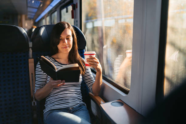 istock Young Woman Drinking Coffee And Reading A Book While Riding In A Train Through Lubeck In Germany 2160567584