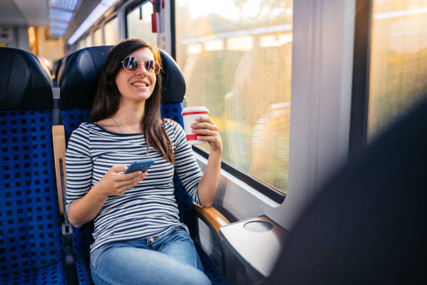 istock Young Woman Drinking Coffee And Using A Phone While Riding In A Train Through Lubeck In Germany 2160567593