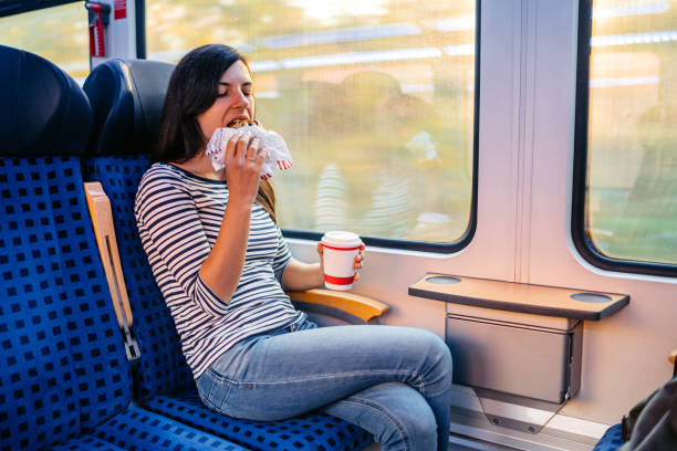 istock Young Woman Drinking Coffee And Eating A Bagel While Riding In A Train Through Lubeck In Germany 2160567743