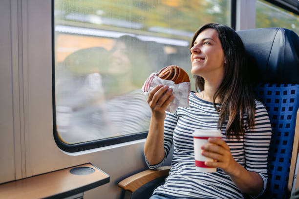 istock Young Woman Drinking Coffee And Eating A Bagel While Riding In A Train Through Lubeck In Germany 2160567800