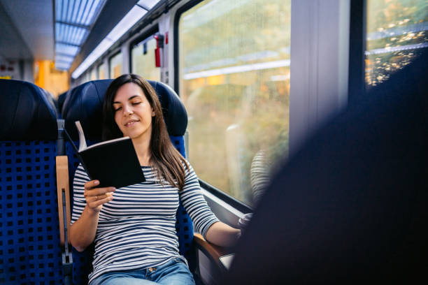 istock Young Woman Reading A Book While Riding In A Train Through Lubeck In Germany 2160567926
