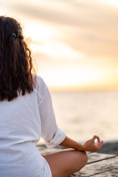 istock Woman meditates on a pier on a beach 2160569225