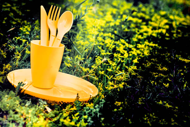 Camping.Yellow plastic dinnerware set.Cup,plate,fork,knife,spoon.Sunny meadow