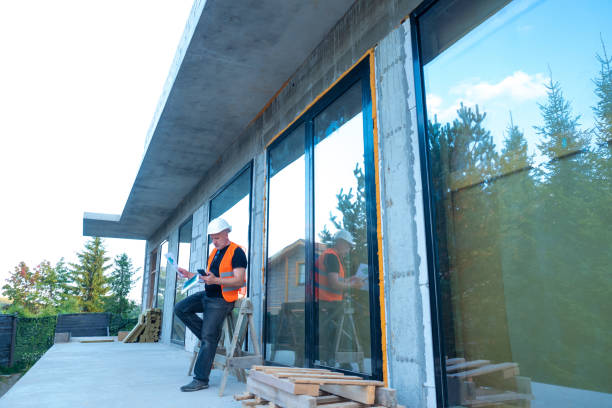 istock The Builder stands next to the building under construction. Panoramic Windows of the house. The study of construction documentation for the building. Engineer builder is studying blueprints. 2160573384