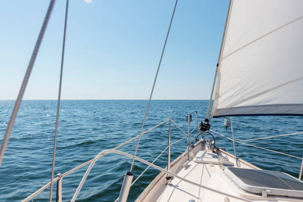istock White sloop rigged yacht sailing at sunset. Clear sky after the storm. View from the deck to the bow, mast, sails. Transportation, travel, cruise, sport, recreation, leisure activity, racing 2160574930