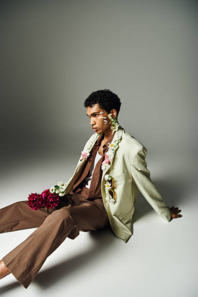 istock A stylishly dressed young African American man sits against a grey backdrop, showcasing a beautiful and diverse image. 2160576185