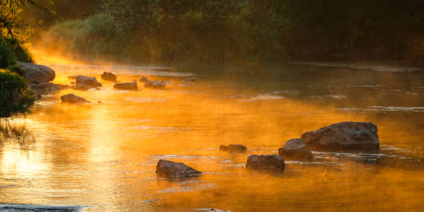 istock Early morning river scene with golden sunlight and mist 2160582859