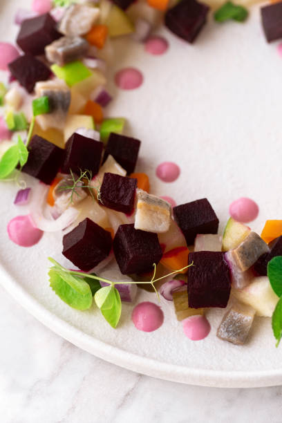Rosolje - Estonian beet and herring salad or Rosoli Finland salad with boiled beets, potatoes, apples, onions, herring fish. Midsummer festive food, Summer solstice wreath symbol. Slavic, Scandinavia, close up rosolje - ensalada estonia de remolacha y arenque o ensalada rosoli finlandia con remolacha hervida, patatas, manzanas, cebollas, arenque. comida festiva del solsticio de verano, símbolo de la corona del solsticio de verano. eslavo, escandinavia, primer p