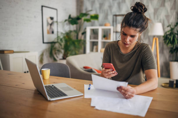 istock Woman multitasking with phone, papers, and laptop 2160585959
