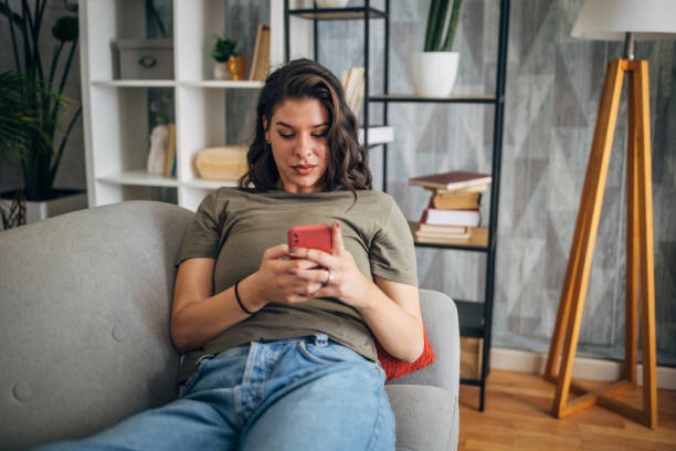 istock Woman relaxing with a smartphone on a couch casually. 2160587301
