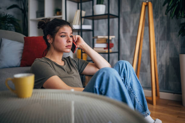 istock Deep in thought woman seated on floor by her couch 2160589289