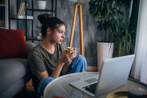istock Person holds coffee mug while looking at laptop screen. 2160590145
