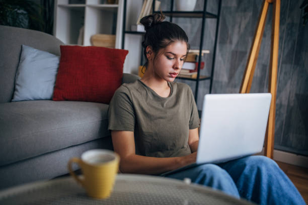 istock Person works on laptop while sitting on floor at home. 2160590921