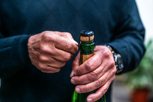 nahaufnahme eines mannes, der eine flasche champagner öffnet - sektkorken stock-fotos und bilder