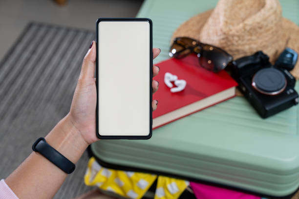 istock A woman's hand holding a smartphone with a white screen, along with clothes being packed into a suitcase in preparation for a weekend trip 2160594152