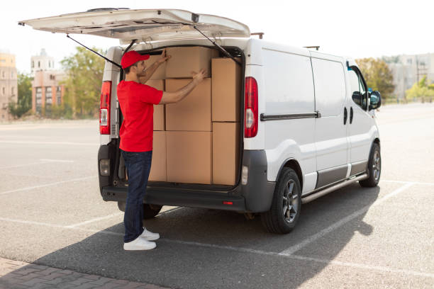 istock Courier man loading cardboard boxes to van, preparing for delivering postal parcel, outdoors shot 2160594353
