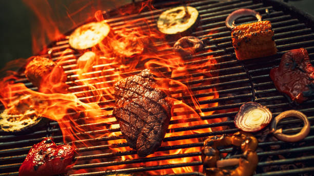 istock Sizzling Steak and Assorted Vegetables Grill Over Intense Flames, Capturing the Essence of Outdoor Barbecue, Smoky Flavors, and Culinary Delight in Vibrant, Fiery Setting. 2160594356