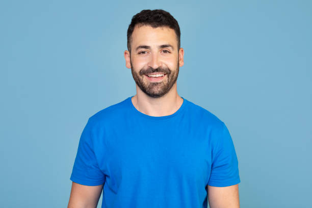 istock Portrait of handsome cheerful man smiling over blue studio background, empty space. Middle-aged bearded man posing for male magazine or blog, youth, healthy lifestyle and male cosmetology concept 2160594868