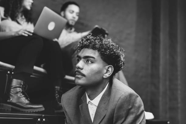 portrait of young businessman in front of other young people with laptops sitting on steps