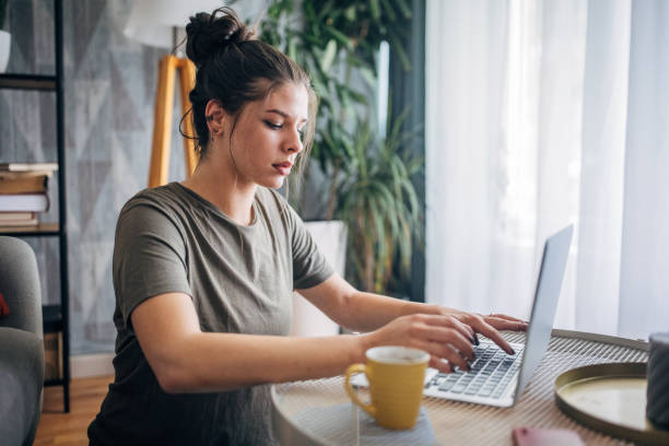 istock Young woman using laptop at home with yellow cup. 2160596051