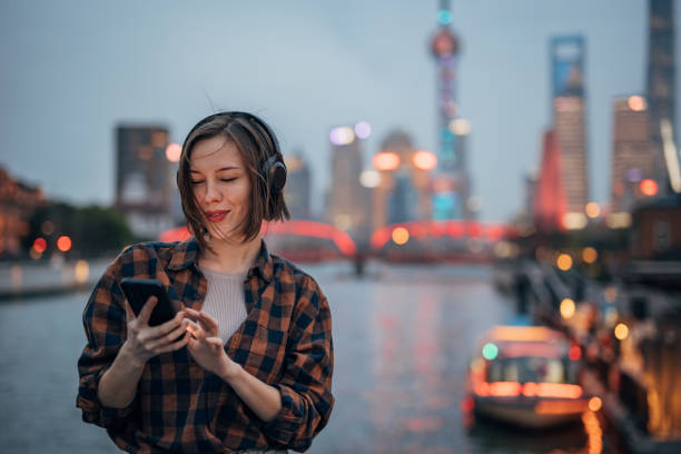 istock Person scrolling through phone, city skyline in background. 2160597341