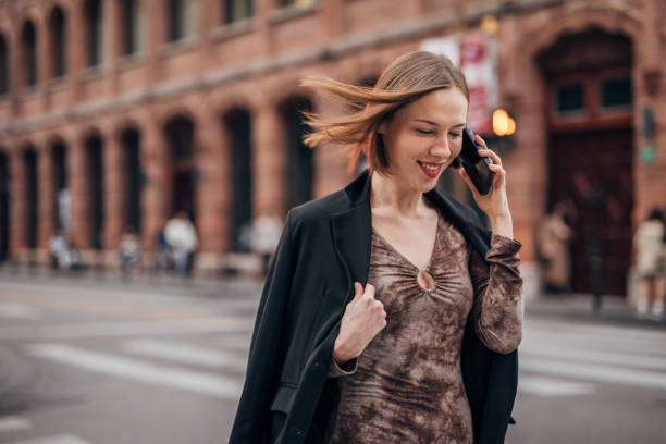 istock Smiling woman on the go, talking on a smartphone 2160597580