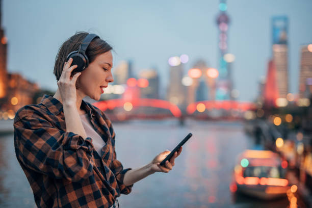 istock Wearing headphones while using smartphone next to city river. 2160597839