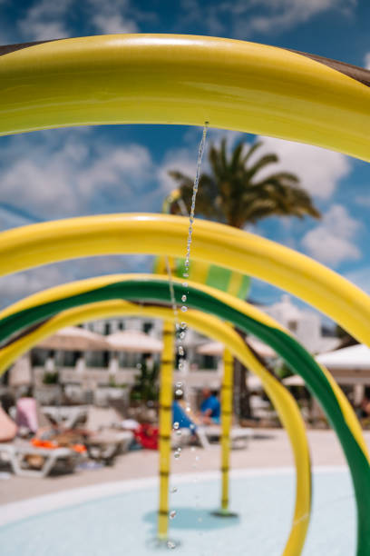 A water slide with a green and yellow section. There are people in the background