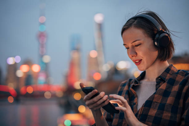 Woman using smartphone by city skyline at dusk hour