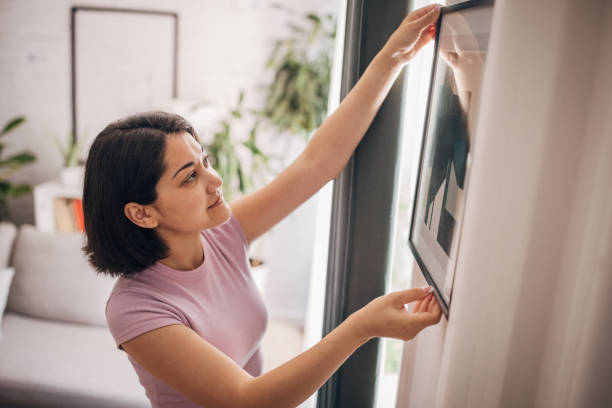 istock Home decorating: Woman adjusting framed art on wall 2160601699
