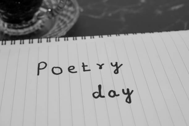 Monochromatic photo of a notebook with the handwritten text 'Poetry day.' Symbolizes creativity, literature, and writing.