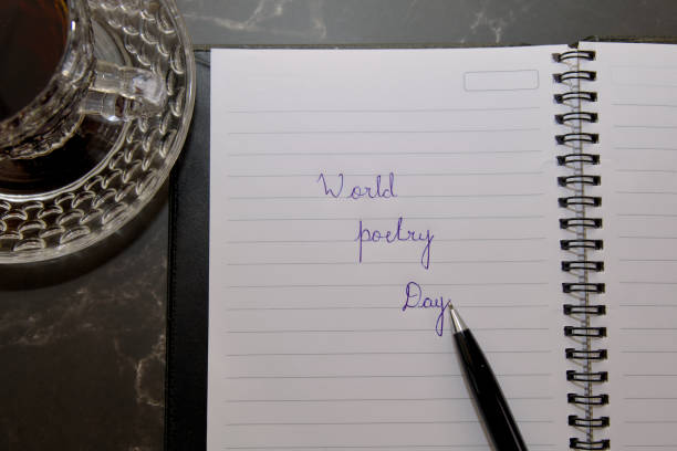 A pen is on a notebook with the words World Poetry Day written on it