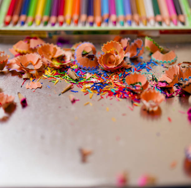 A pile of colored pencil shavings on a table. The pencil shavings are scattered in various colors, creating a vibrant and colorful scene. Concept of creativity and artistic expression