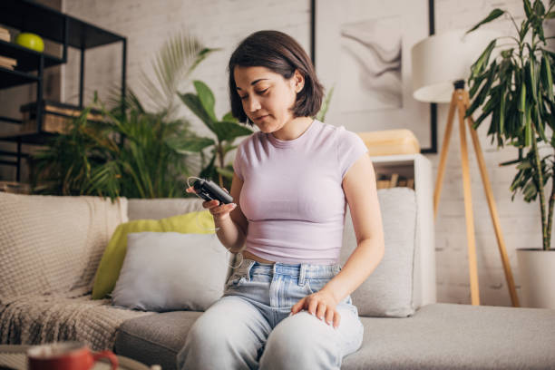 istock Woman sitting on a sofa looking at a device screen. 2160607397