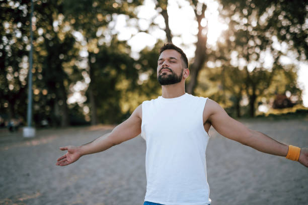 istock Man stretching arms at scenic sunset beach location 2160609049