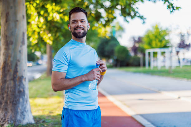 istock Man hydrated and happy while jogging in park. 2160609881