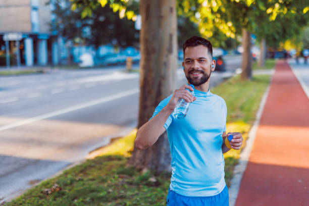 istock Man takes a break to hydrate during his jog. 2160609893