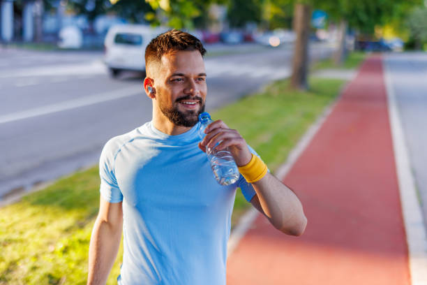 istock Man in blue shirt drinking water during morning walk 2160609916