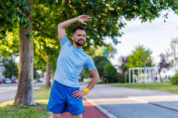 istock Man stretching under trees on a sunny urban pathway 2160609957