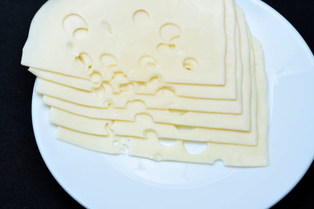 Cheese cut into flat slices on a plate. Delicious cheese.