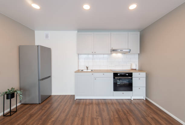 istock Scandinavian Style Cozy Modern Open Bright Minimalism Kitchen Home Interior. Oven, Faucet, Kettle, Fridge and Furniture in Background. Dark Brown Flooring. Flower. White Cabinets 2160610316