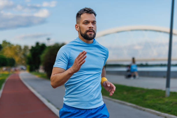 Man running determinedly on park pathway in blue gear