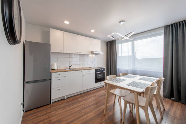 istock Scandinavian Style Cozy Modern Open Bright Minimalism Kitchen Home Interior. Oven, Faucet, Kettle, Fridge and Furniture in Background. Dark Brown Flooring. White Cabinets 2160610425