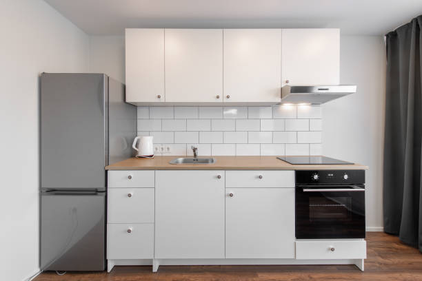 istock Scandinavian Style Cozy Modern Open Bright Minimalism Kitchen Home Interior. Oven, Faucet, Kettle, Fridge and Furniture in Background. Dark Brown Flooring. White Cabinets 2160610440