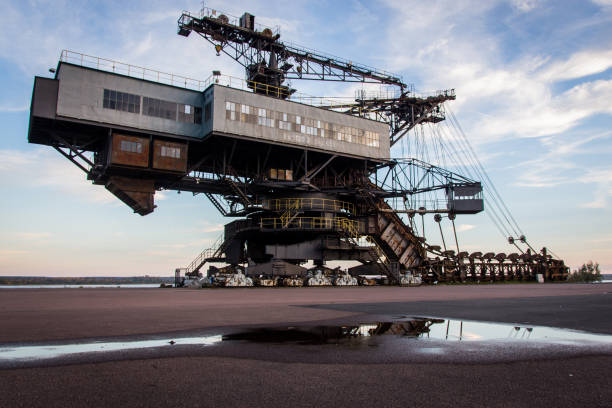 Wheel Bucket Excavator Working At Coal Mines with coal-fired power station in background.