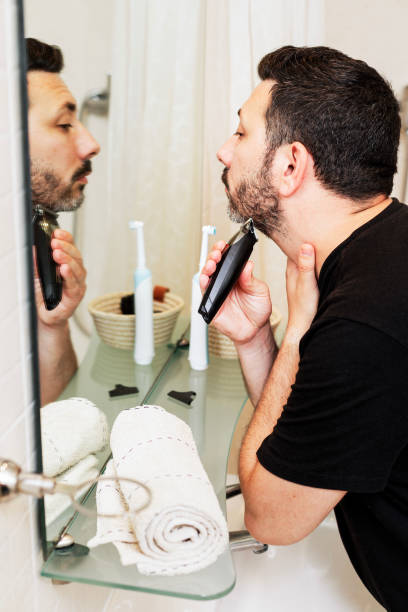 istock 40-Year-Old Man Grooming Beard in Bathroom Mirror 2160613941