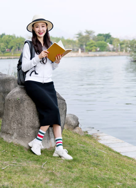 Young woman reading book by the lake.
