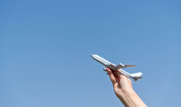 istock Woman hand holding model airplane under blue sky 2160614852