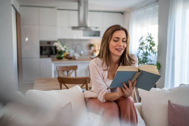 istock A woman sits on her favorite sofa, enjoying a peaceful moment while reading a book 2160622135