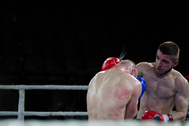 Close-up of female boxer knocked out in final round. Two young girls boxing on ring and one girl lying on floor after strong blows of her rival, loosing match. Extreme sport and womens boxing concept